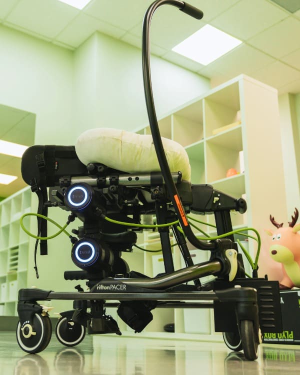 A side view of the Trexo Plus robotic gait trainer on a Rifton Pacer frame, used for intensive gait training in pediatric physiotherapy.